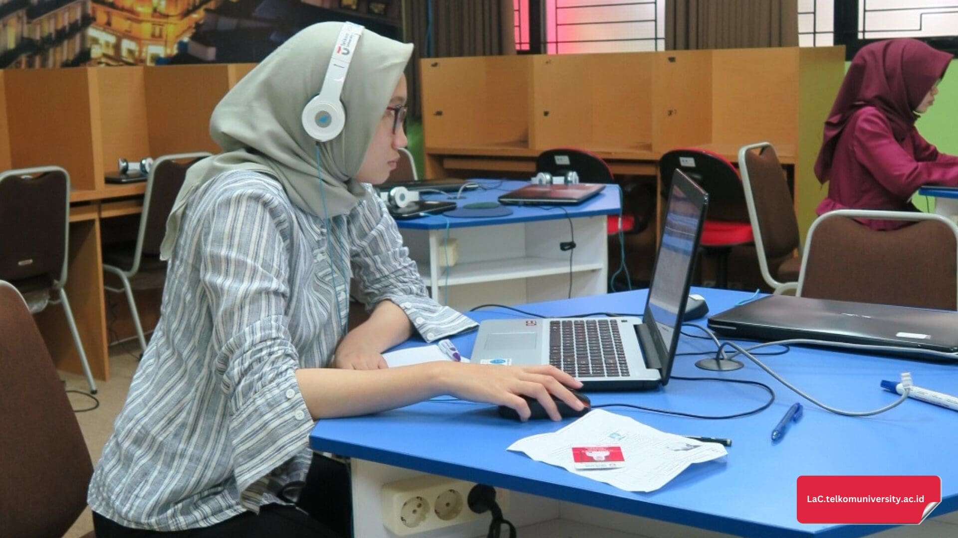 Seorang mahasiswa yang sedang berlatih soal Listening TOEFL ITP dengan headphone