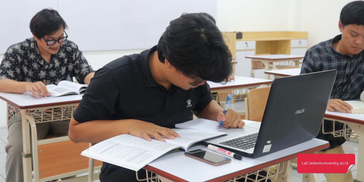 Mahasiswa belajar tenses bahasa Inggris dengan buku dan laptop di meja belajar