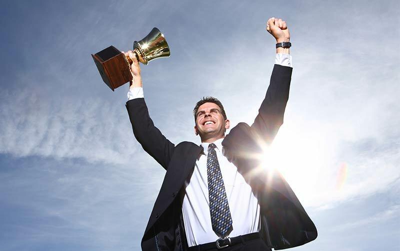 Seorang lelaki yang sedang mengangkat piala dengan riang